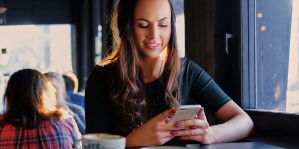 A woman texting an SMS in a cafe.