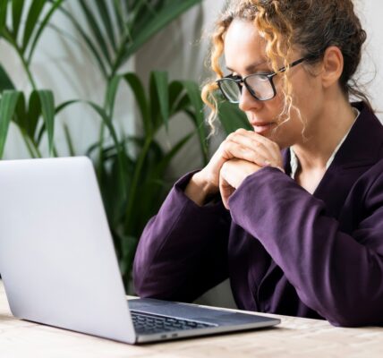 Professional entrepreneur reading email on laptop at the desk wearing glasses