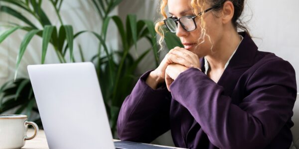 Professional entrepreneur reading email on laptop at the desk wearing glasses